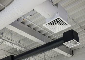 Two ventilation duct systems with grilles under ceiling in commercial building. Supply and exhaust